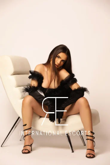 Beautiful Brazilian escort in London Addie is sitting on a chair with her legs wide open 