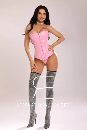 A picture of a very sexy brunette escort wearing a pink corset 