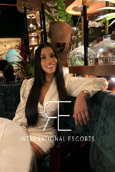 Sexy brunette escort from Brazil Mannu is sitting in a restaurant in London called Amazonico