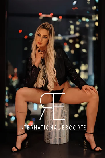 London escort Carmen sat on a white box by a window 