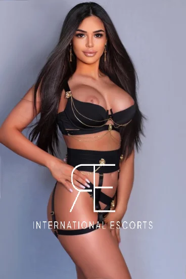 Busty brunette London escort Juliet-May is pictured wearing sexy black lingerie 