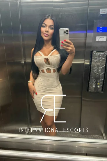 Slim busty Brazilian London escort wearing a sexy dress 