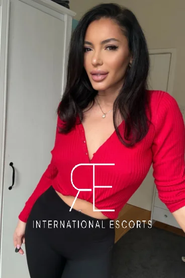 Brunette London escort Kylie is wearing a red top 