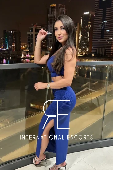 Brunette escort wearing a blue dress looking very sexy 