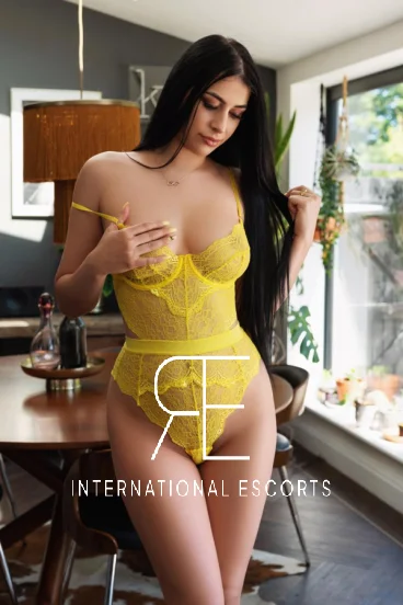 A London escort stood in a kitchen wearing yellow lingerie 