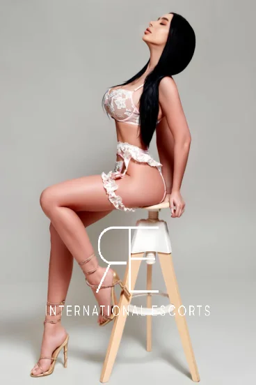 High class London escort Robyn is sitting on a stool 