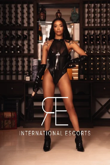 London escort Asha wearing boots and a black dress 