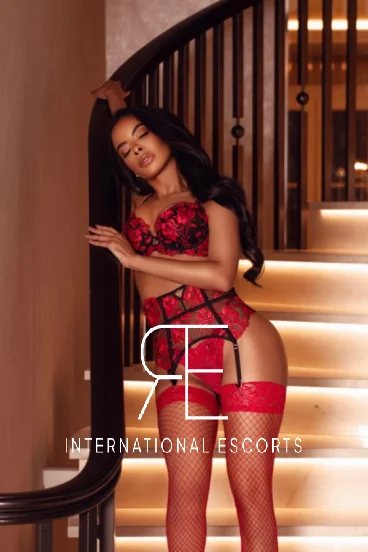 Ebony escort wearing red and black lingerie and looking asleep 