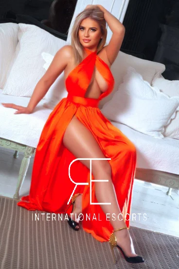 Curvy blonde London escort Addison wearing a orange dress 