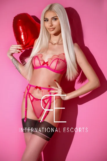 Slim blonde escort with natural boobs holding a ballon 